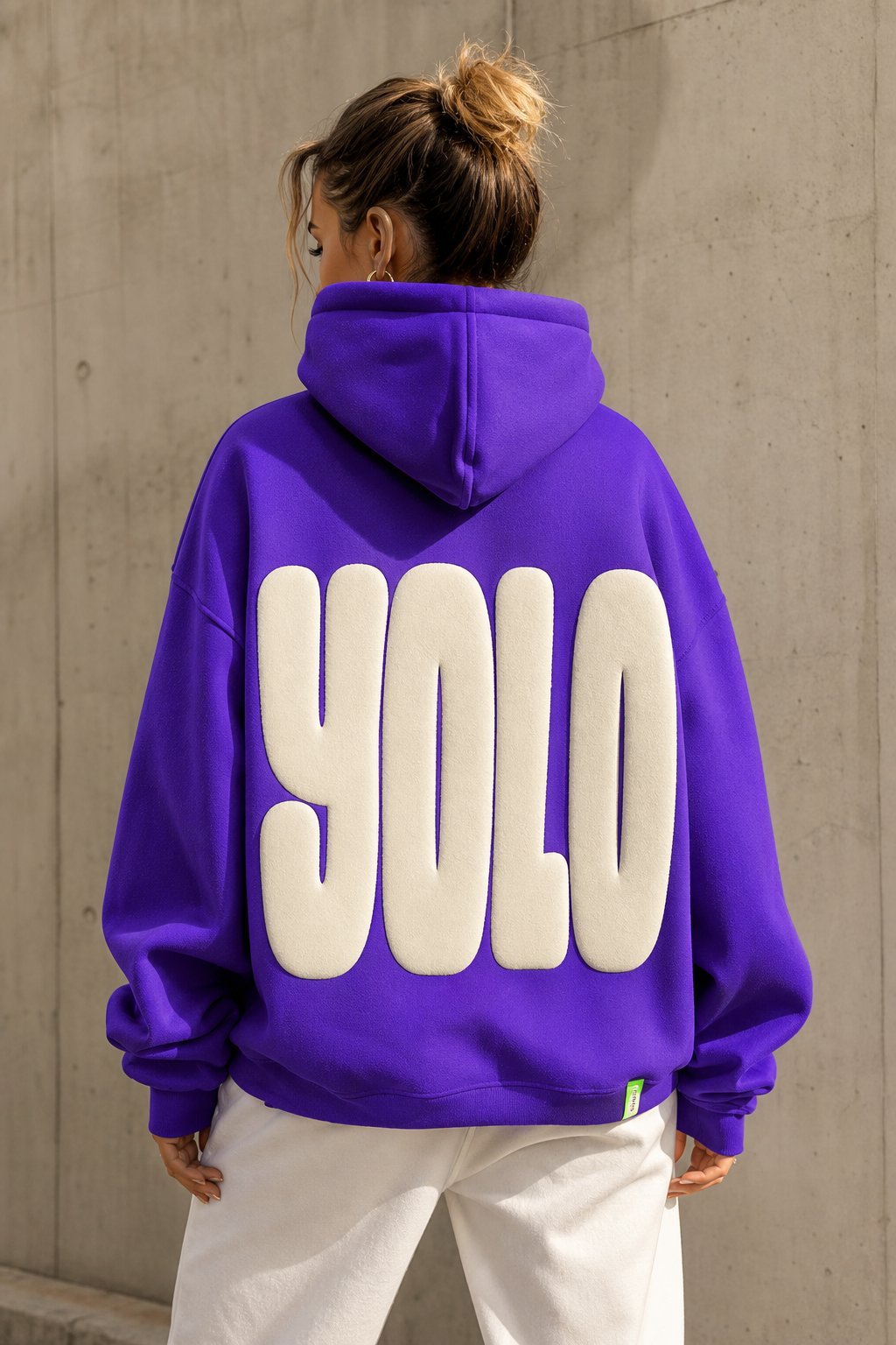 YOLO purple oversized hoodie with cream puff-print wordmark across the back