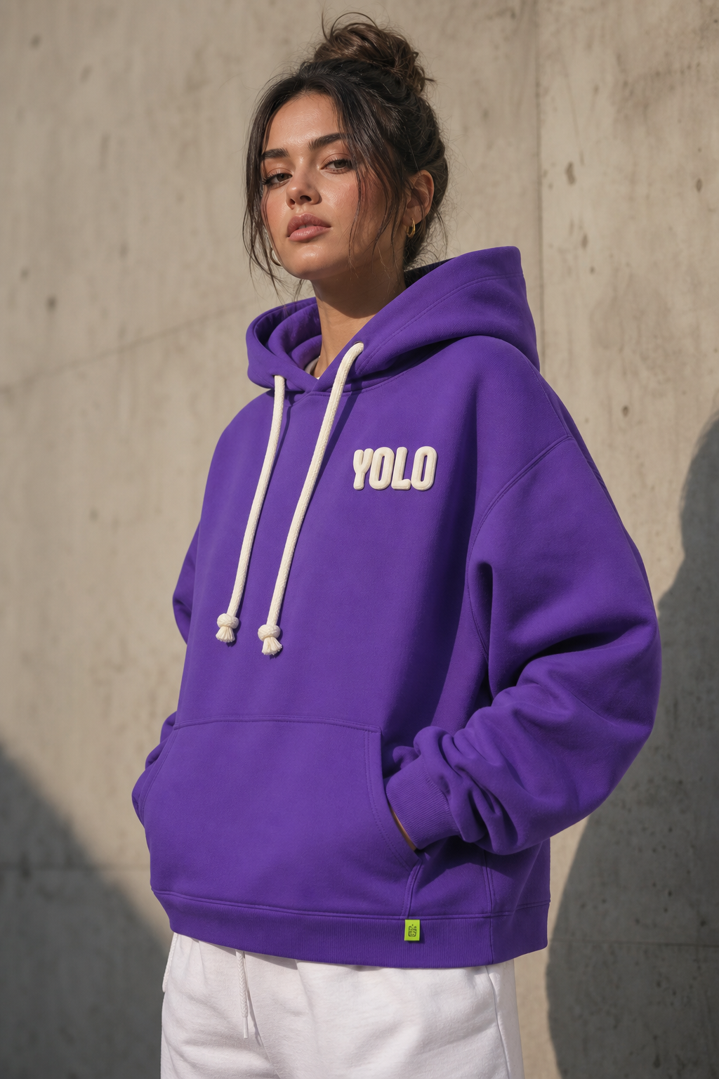 YOLO hoodie chest detail — cream puff-print wordmark on brand purple